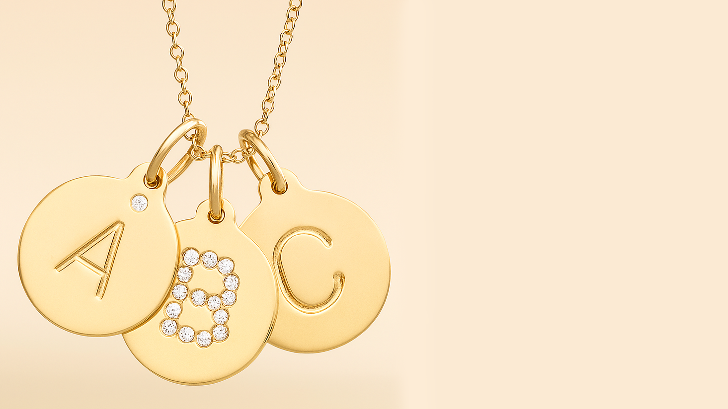 Gold necklace with three round pendants labeled A, ABC, and C on a beige background