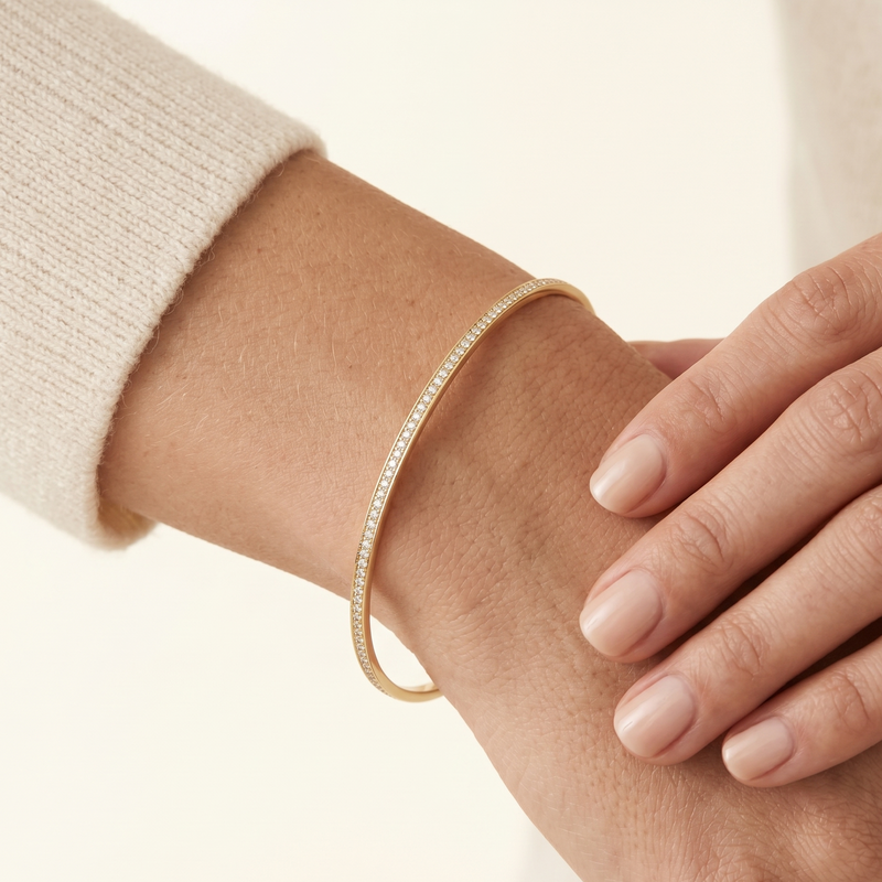 Gold bracelet on a wrist with a neutral background