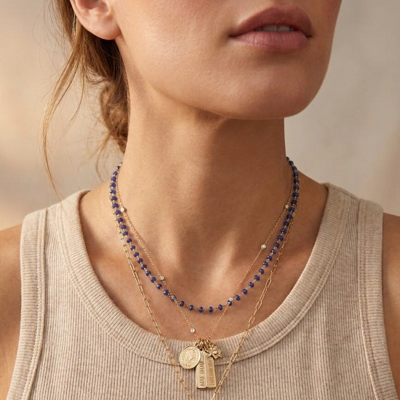 Necklace with pendants on a person wearing a beige tank top against a neutral background