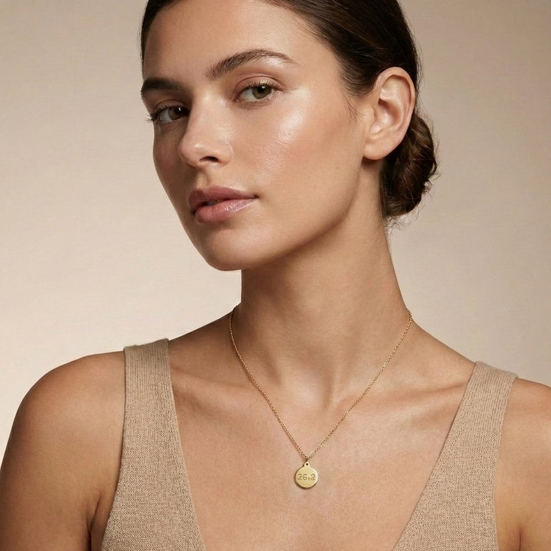 Woman wearing a gold necklace with a beige background