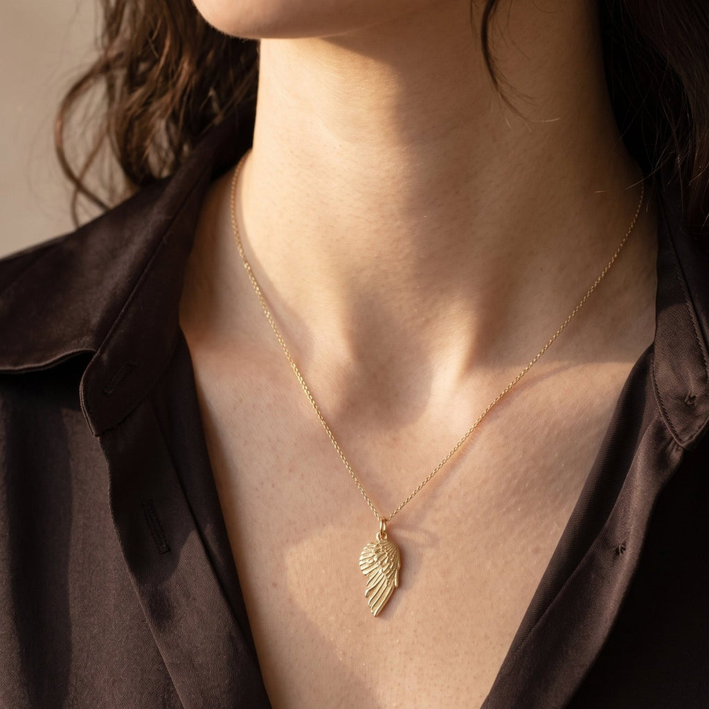 solid 14k gold angel wing charm pendant on a model.