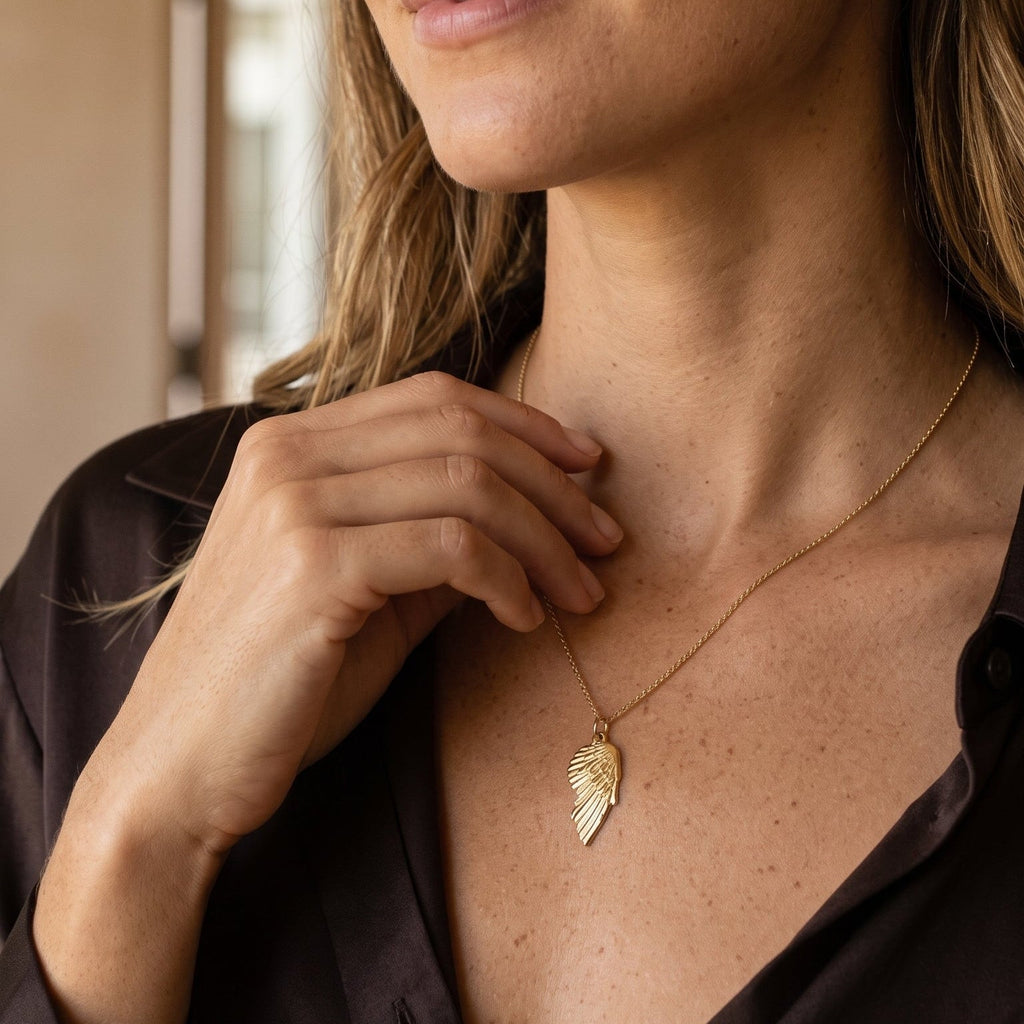 Large angel wing charm 14k gold on a models necklace.