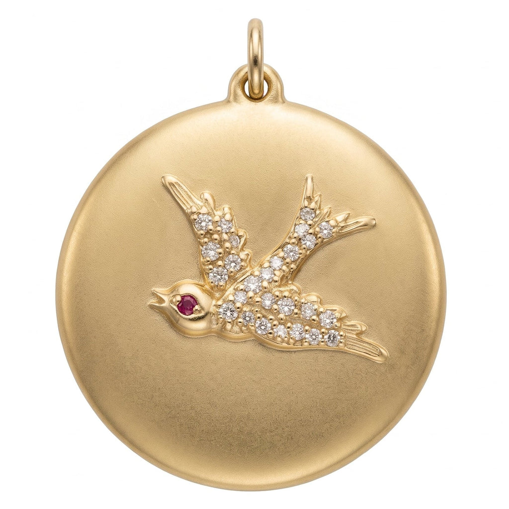 Swallow disk coin charm made from solid 14k gold with pave diamonds and a single ruby eye.