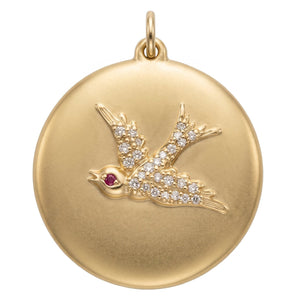 Swallow disk coin charm made from solid 14k gold with pave diamonds and a single ruby eye.