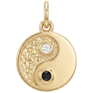 Gold yin yang pendant with gemstones on a white background
