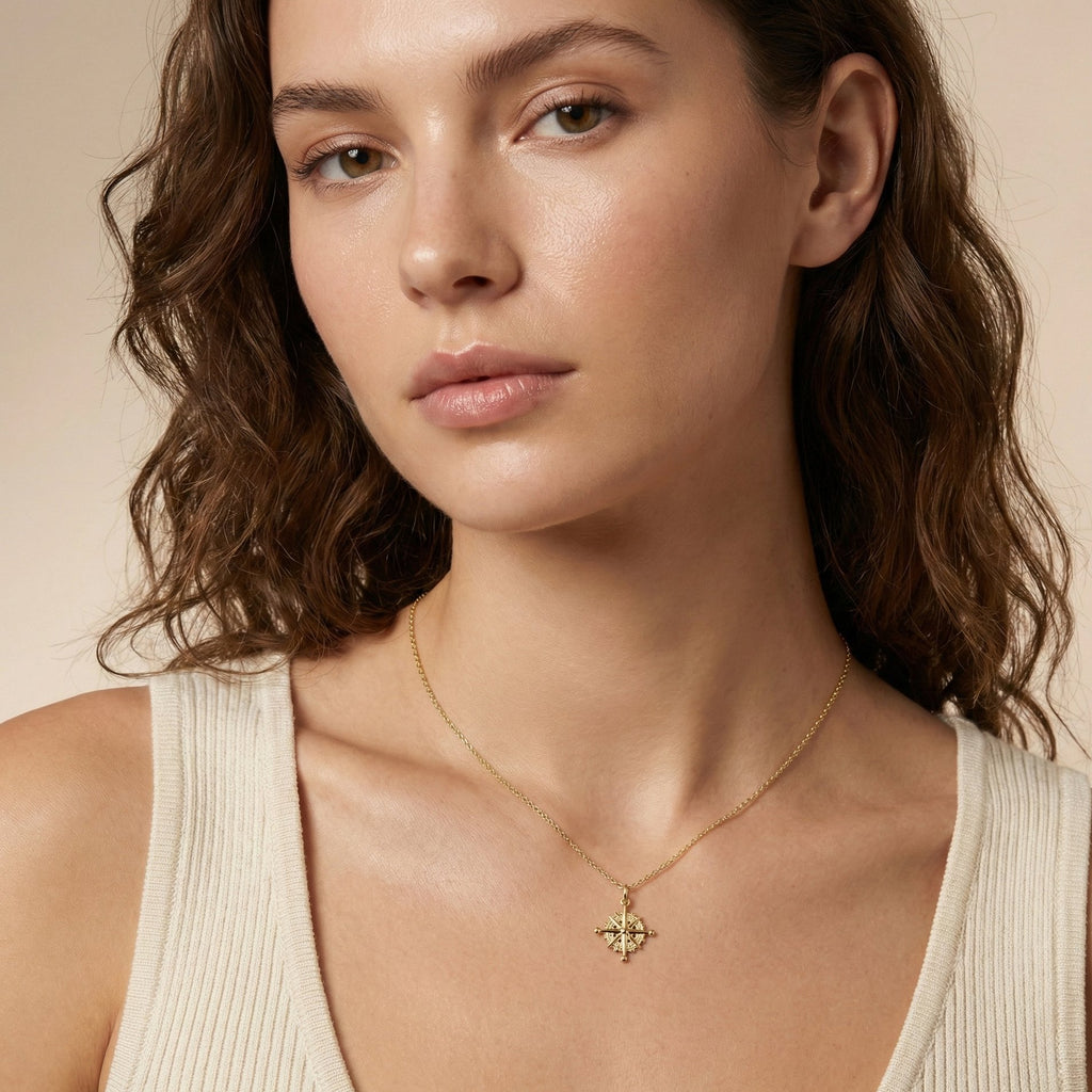Woman wearing a gold necklace with a pendant against a neutral background